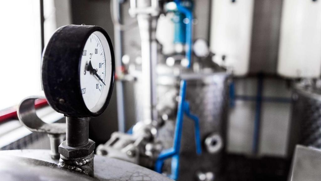 Distillery equipment. Temperature gauge sits atop metal vessel.