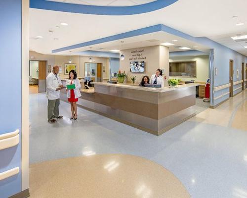 Interior view of nurses station at Jupiter Medical Center. Nurse and doctor standing nearby discussing documents.